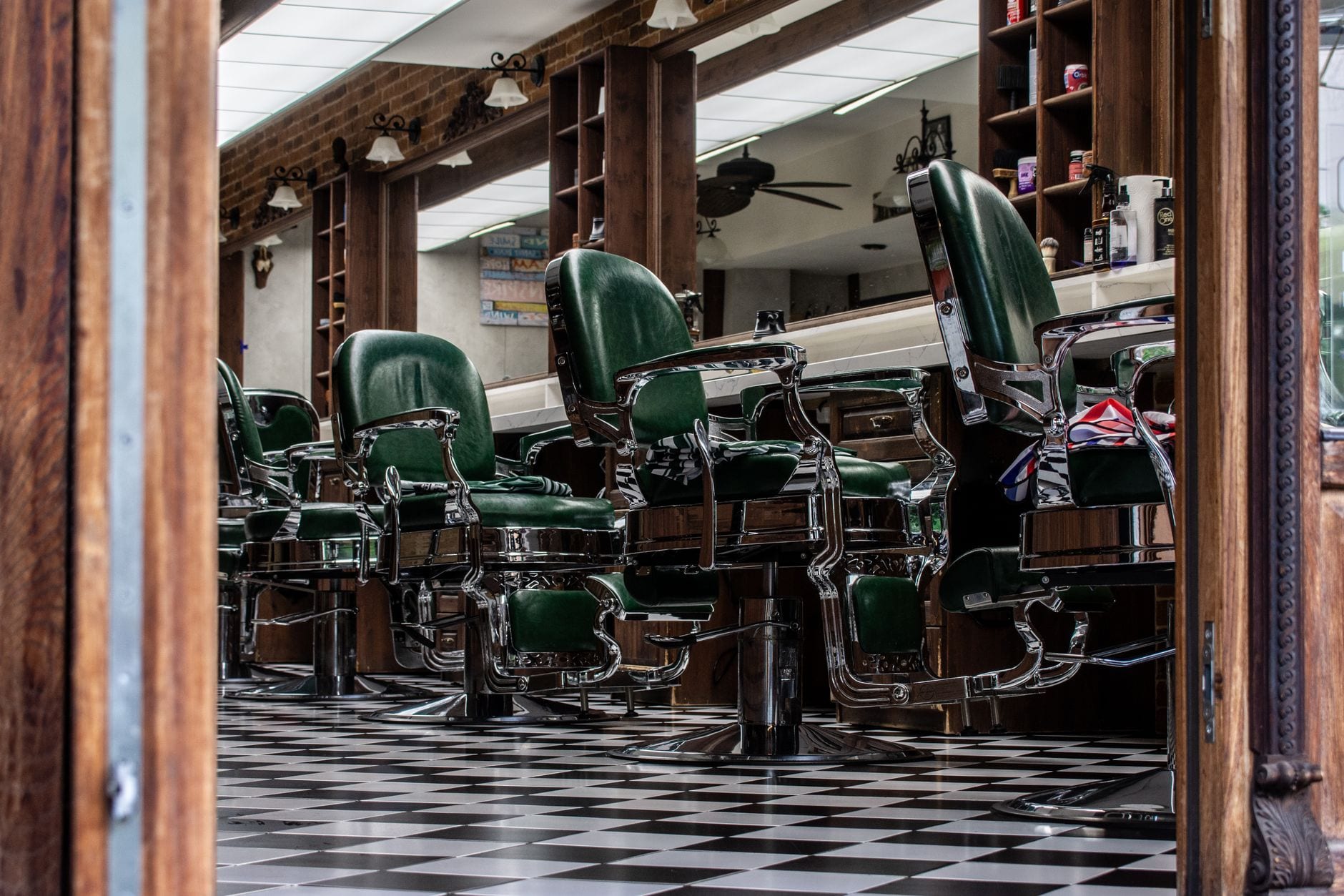 Vintage-style barber shop interior with green leather chairs and a checkered floor